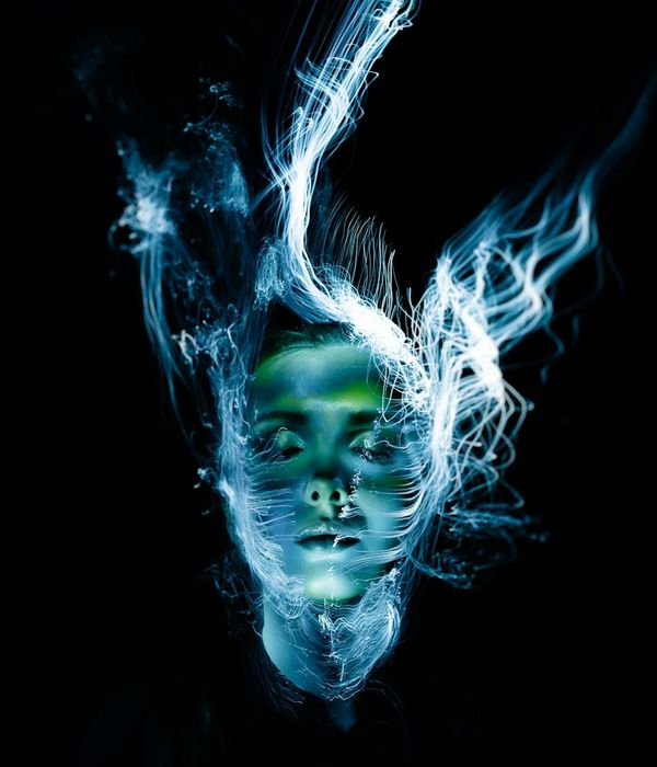 Woman in a calm, fluid motion pose against a dark background with ruby light accents.